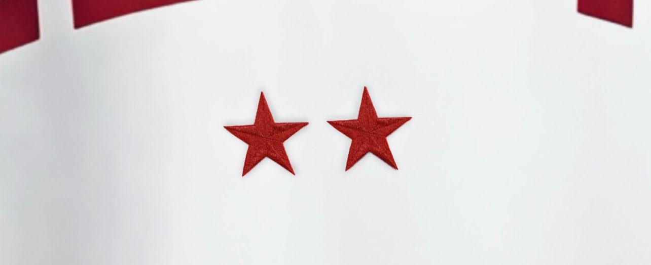 Detalle de las dos estrellas rojas bordadas de la camiseta Velura